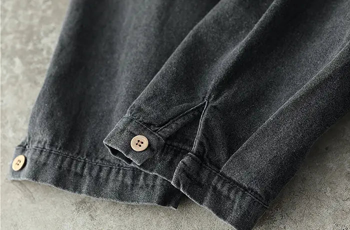 Dark gray denim pants with light brown wooden buttons at the cuffs featured as part of a retro artistic plus size dark gray denim tunic dress.