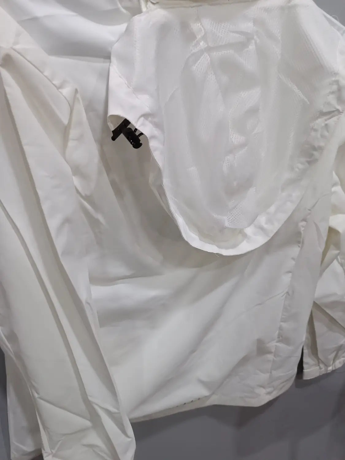 White waterproof hiking jacket for men with a hood and a small black zipper pull on the front pocket designed as a windbreaker.
