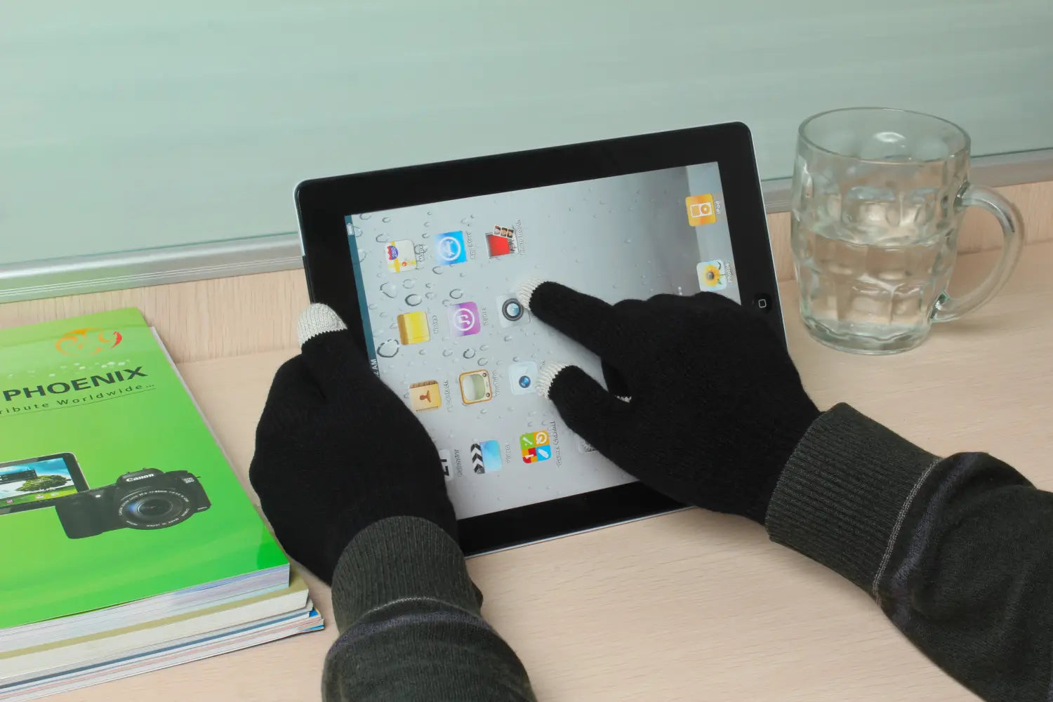 Ein schwarzes Touchscreen-Tablet mit glänzender Oberfläche und sichtbaren App-Symbolen, das die Verwendung von Touchscreen-Winterhandschuhen für Damen und Herren demonstriert.