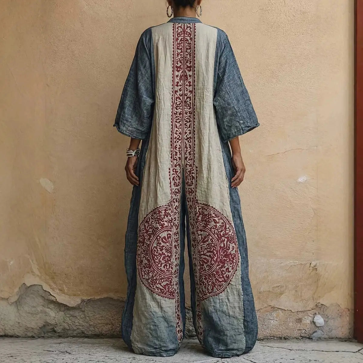 Pantalon bohémien à jambes larges imprimé présenté de dos, avec une longue combinaison denim et couleur crème fluide, ornée de motifs brodés rouges complexes.