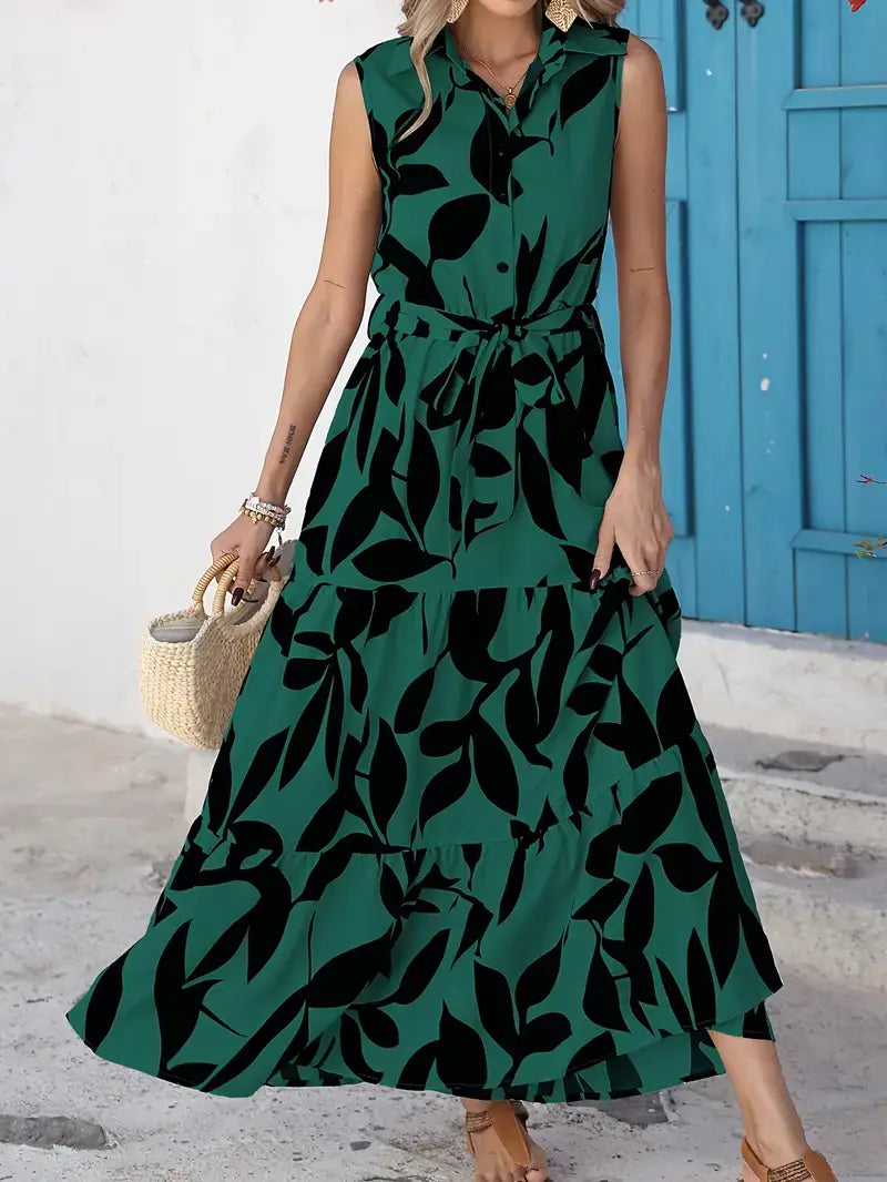 An elegant sleeveless green maxi dress with a black leaf pattern and a tied waist detail.