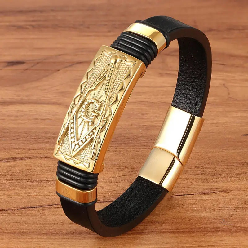 Black leather scorpion bracelet with a gold-toned rectangular plate engraved with a sunburst design and matching magnetic clasp.