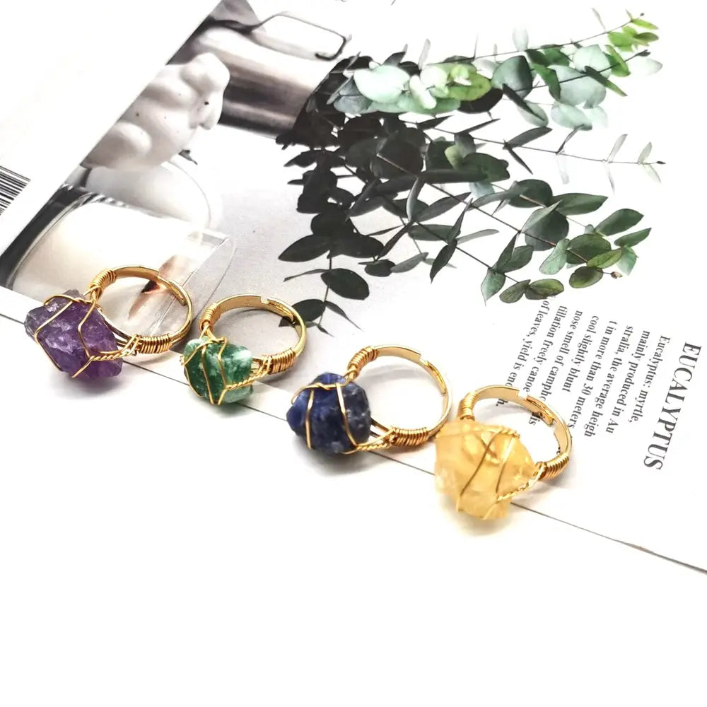 Handcrafted raw gemstone gold wire wrapped adjustable ring featuring four unique rings with purple amethyst, green aventurine, deep blue lapis lazuli, and yellow citrine raw crystal centers in gold-toned metal.