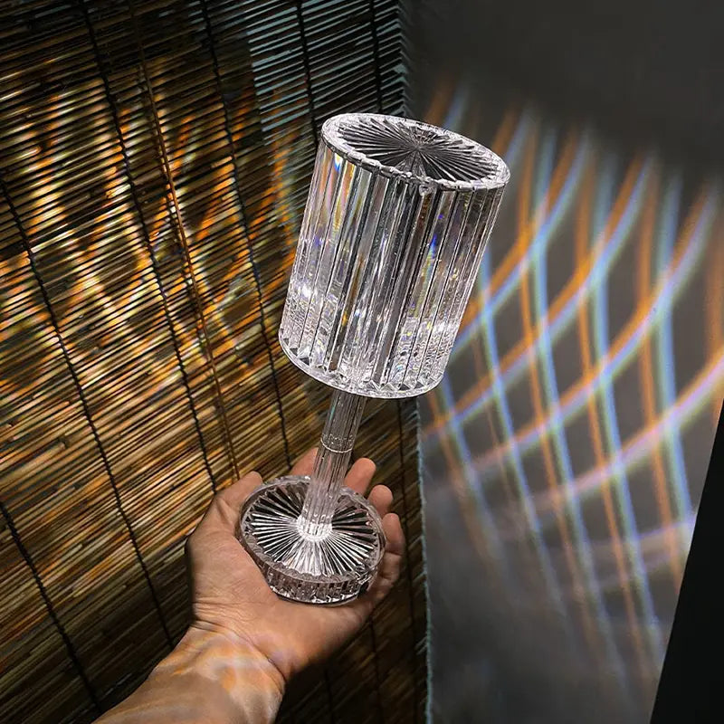 Crystal table lamp with clear faceted crystal cylindrical body and fluted base featuring 3 way dimmable touch control night light functionality.