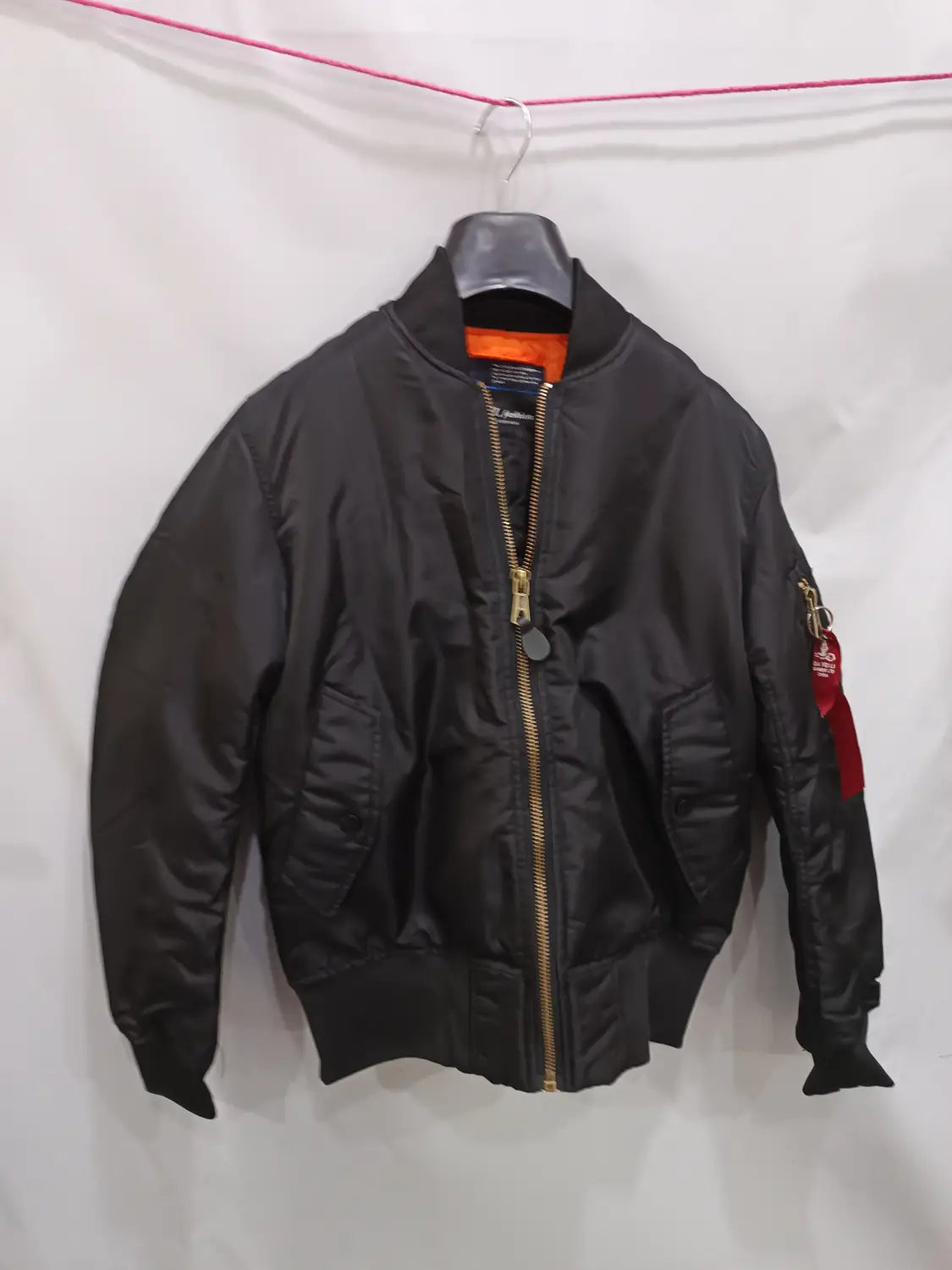 Men’s pilot cotton bomber jacket in black matte nylon with gold zipper and red sleeve patch featuring a classic military-inspired design.