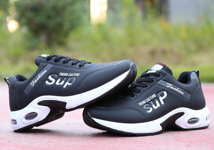 Men’s casual sportswear leather running shoes in black and white featuring fashion and trend culture sup branding on the side.
