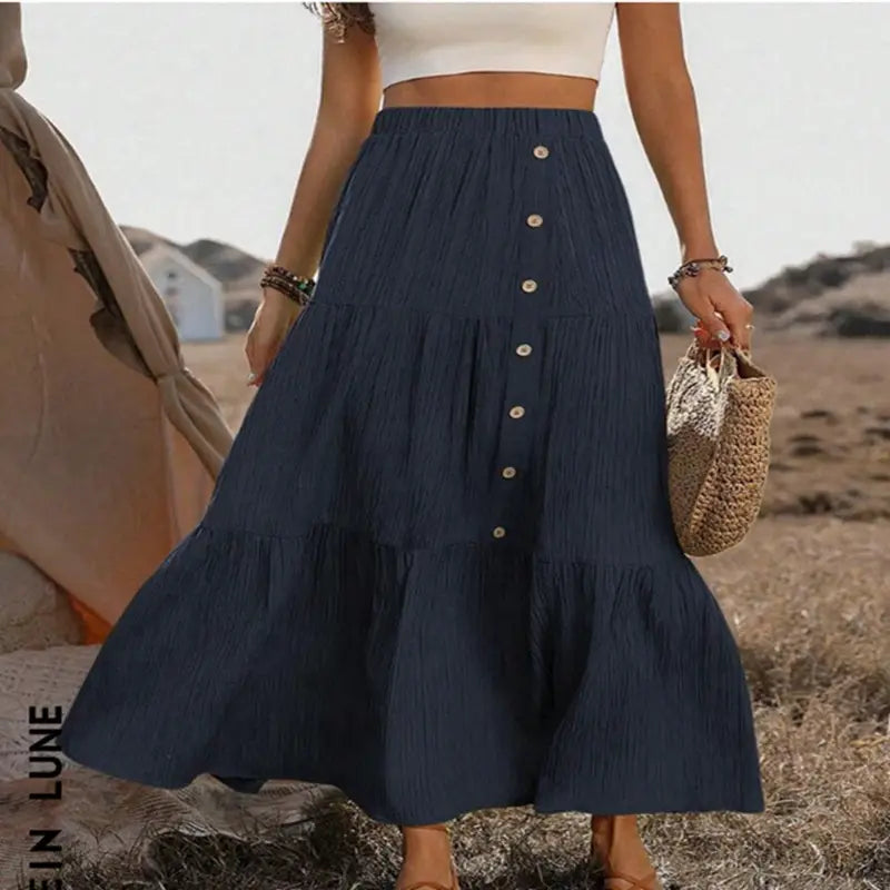 A navy blue tiered maxi skirt with a button front design and subtle pleats perfect for lightweight casual wear.