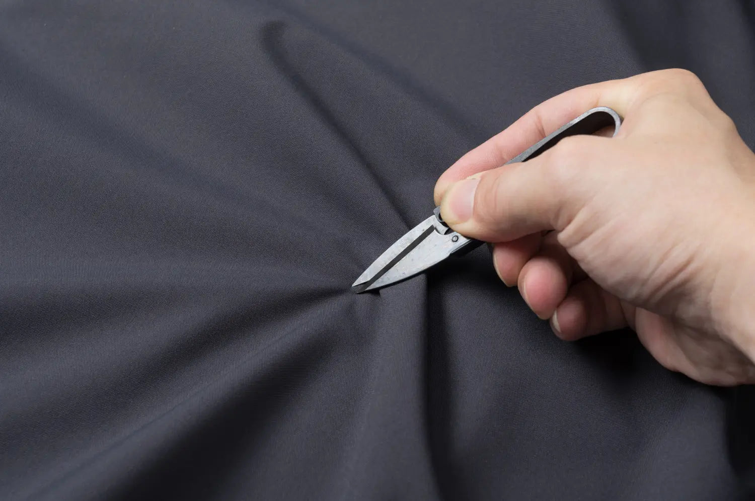 Couteau de poche pliant élégant à finition argentée, au design compact et à lame tranchante, associé à une veste de plein air imperméable à capuche pour hommes et femmes.