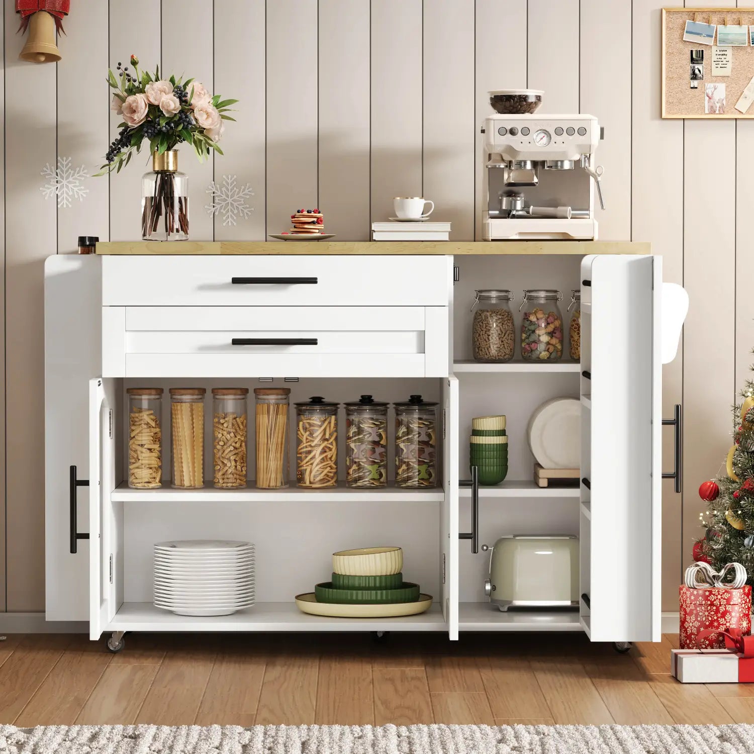 White kitchen cart with black handles and open shelving featuring glass jars filled with pasta on the top shelf and stacked plates below in a mobile kitchen island with foldable worktop and wheels.