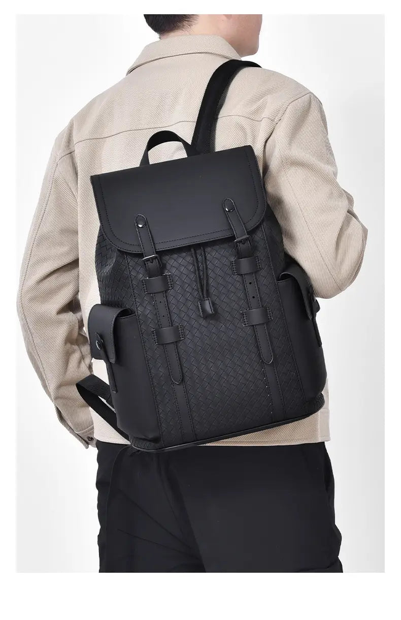 Black leather men’s business travel backpack with woven texture and flap closure featuring a laptop sleeve.