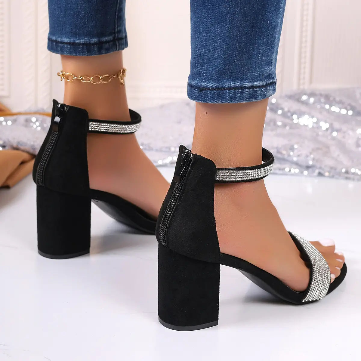 Black suede rhinestone block heel sandals with ankle strap featuring sparkling rhinestone accents along the strap and a chunky block heel.
