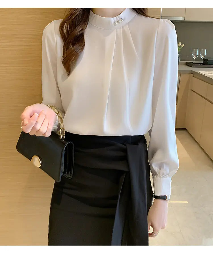 Blouse ample en satin ivoire pour femmes, à encolure haute et accents de boutons perle, avec des manches longues et des poignets froncés.