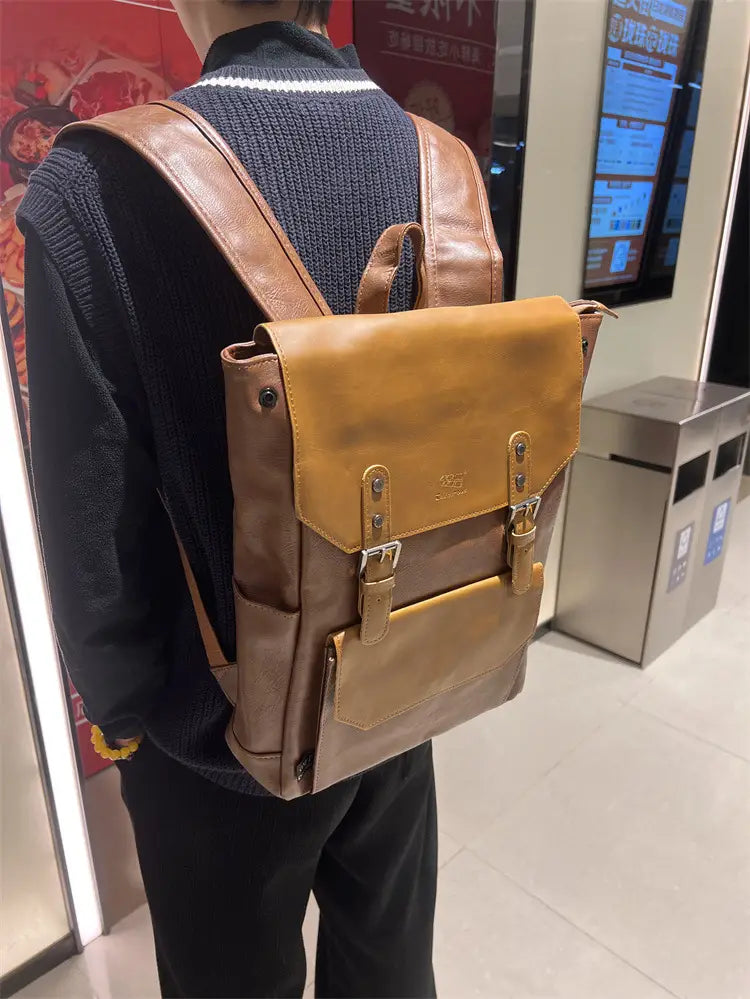 Vintage leather college backpack in two-tone brown leather with a tan front flap and brass hardware designed for large capacity and travel use.