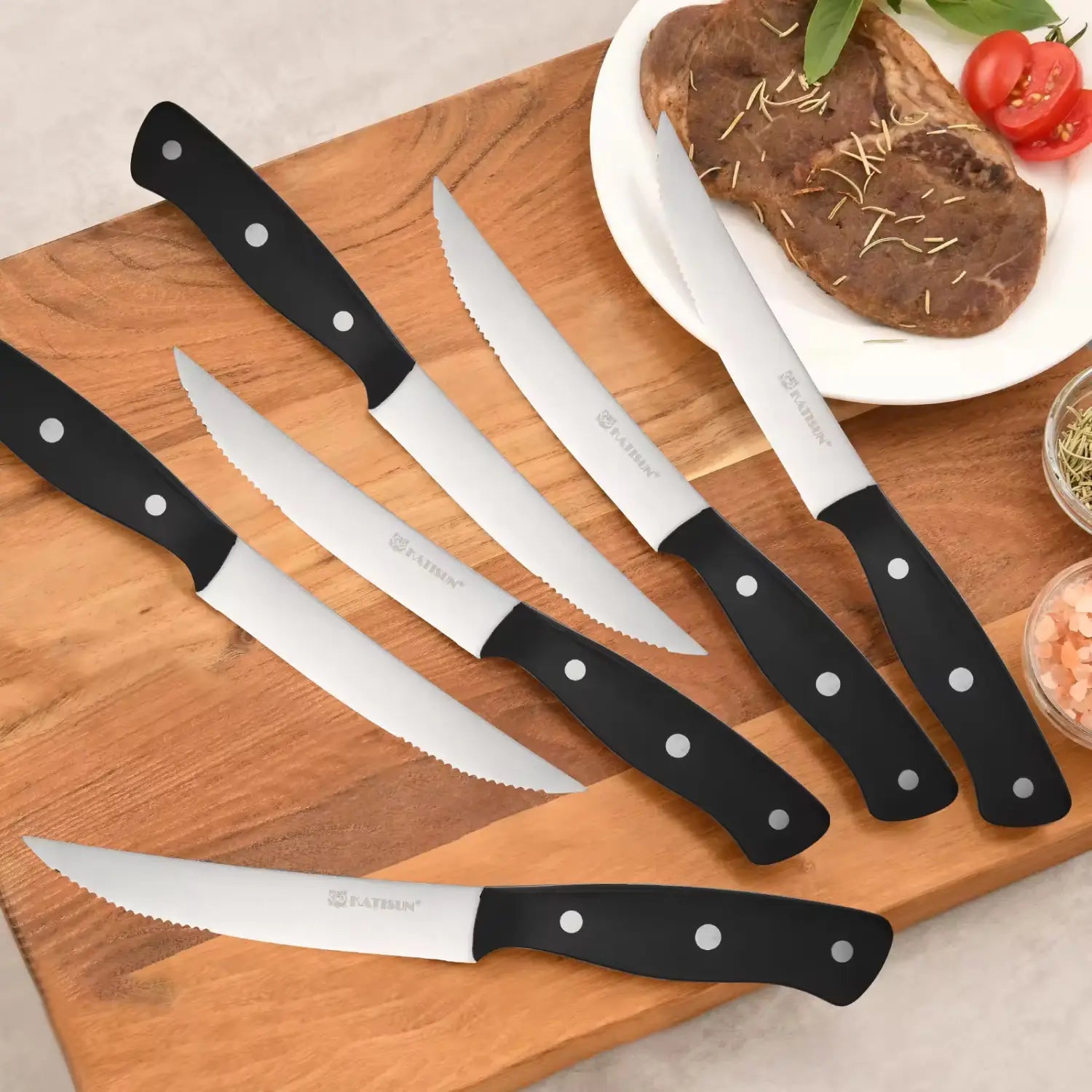 Ensemble de six couteaux à steak à poignée noire, avec des lames en acier inoxydable et acier au carbone, présentant un design élégant et moderne.