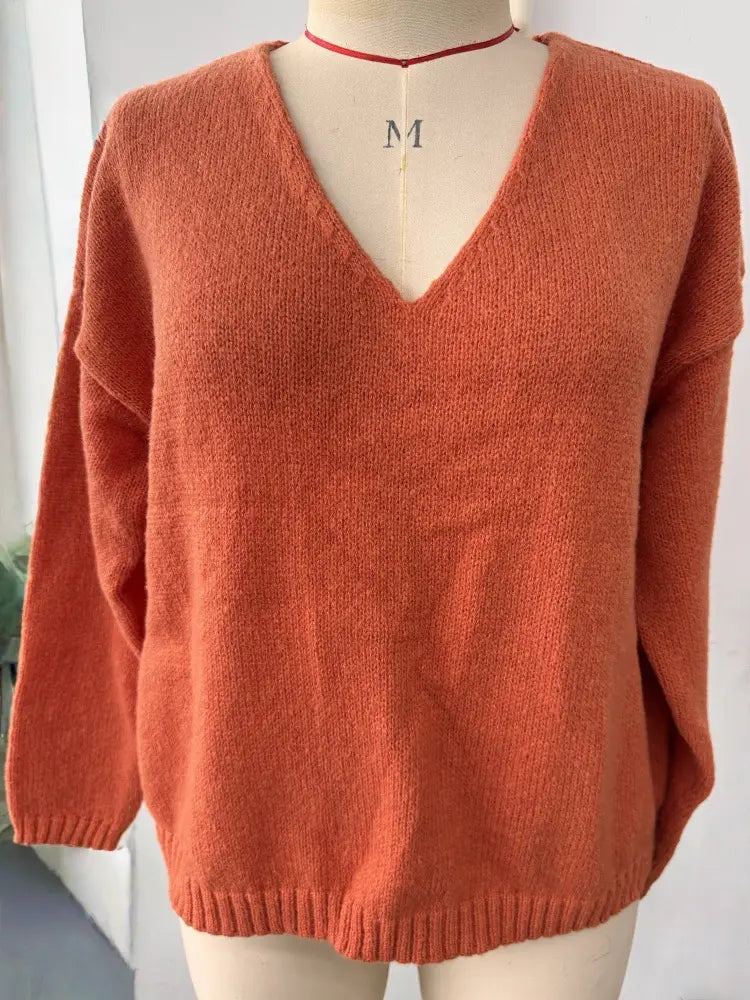 Gemütlicher Strickpullover mit V-Ausschnitt und überschnittener Schulterpartie in Rostorange, mit weicher Textur und gerippten Bündchen.