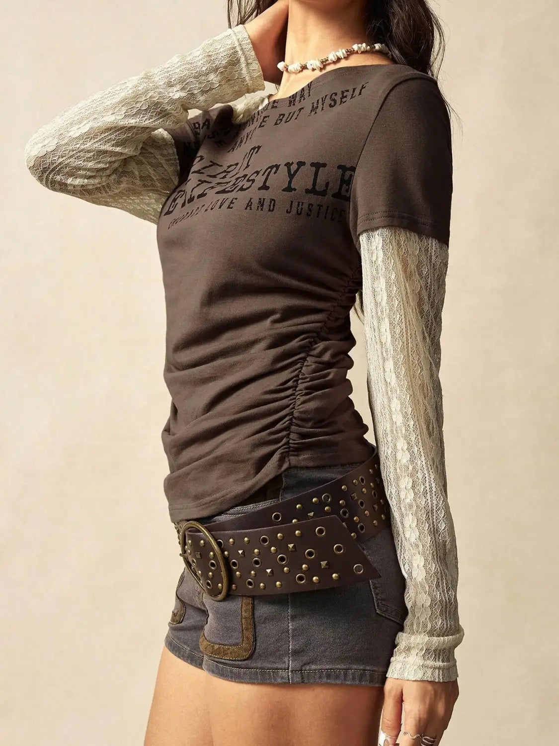Dark brown lace layer off shoulder knitted top featuring ruched fabric with contrasting sheer lace sleeves and bold black graphic text across the chest.