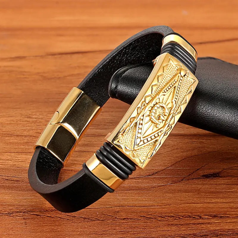 Black leather scorpion bracelet with gold-toned rectangular magnetic clasp featuring intricate geometric and sunburst engravings.