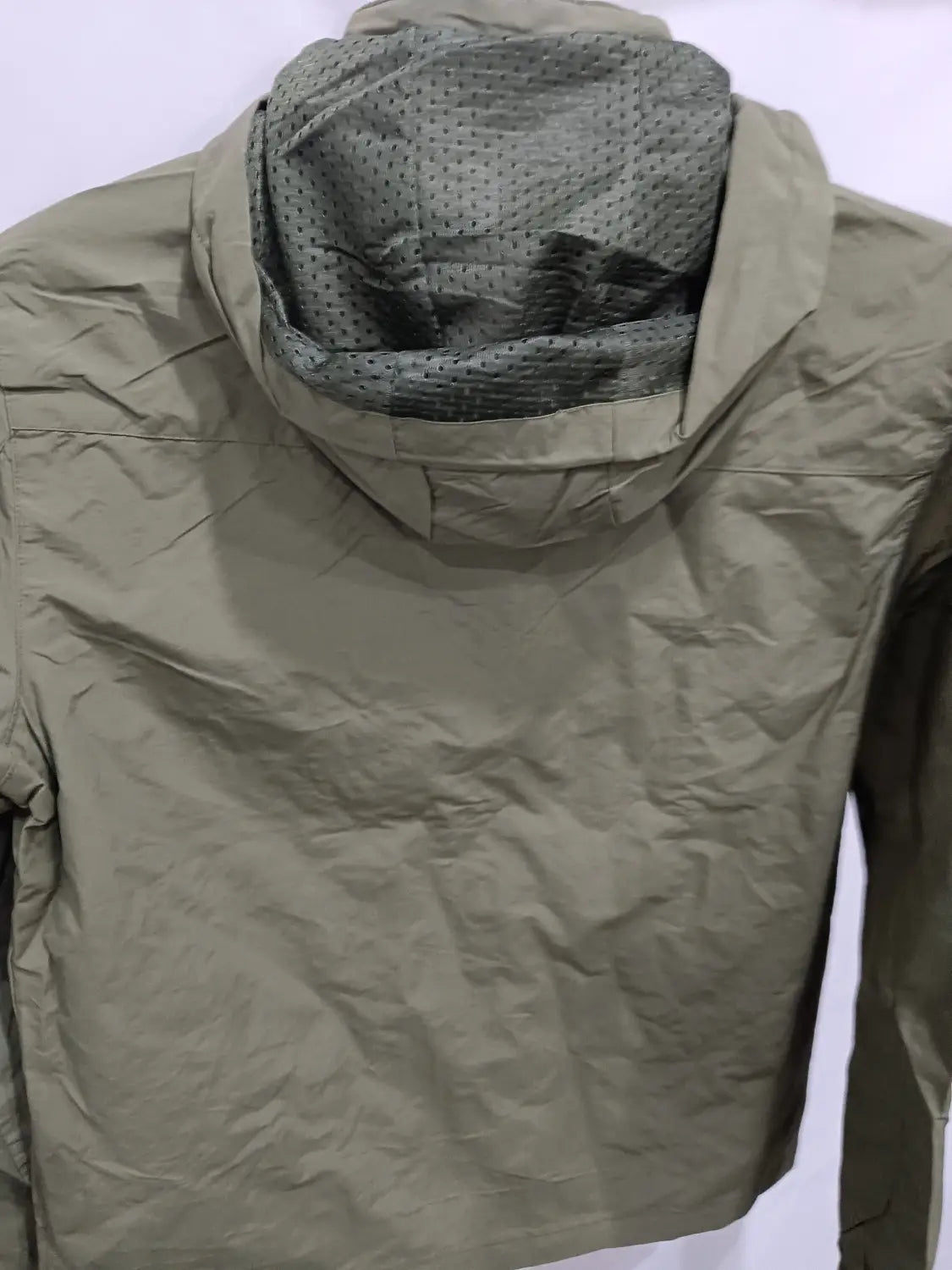 Chaqueta de senderismo con capucha impermeable color verde oliva, con forro interior perforado, diseñada para actividades al aire libre.