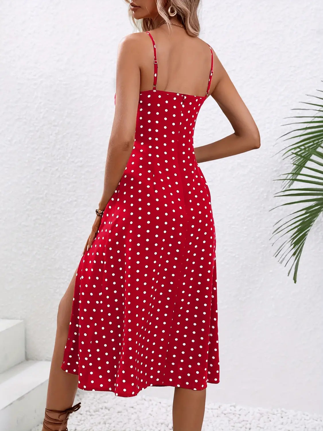 Red polka dot midi dress with thin spaghetti straps and a side slit made from lightweight fabric suitable for summer wear.