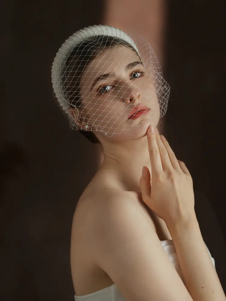 A delicate white beaded vintage French Hepburn bridal veil headband with a fine mesh veil.