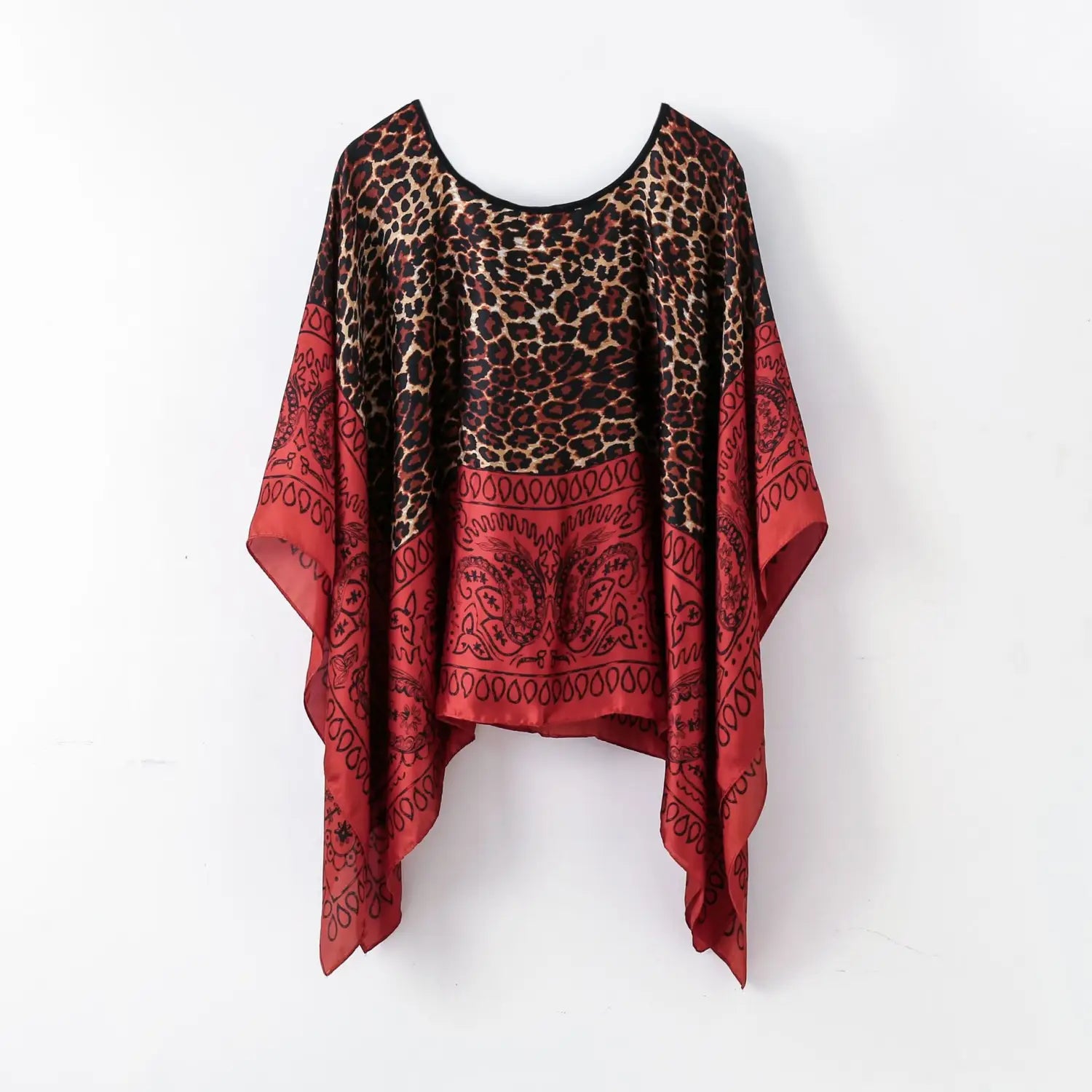 A flowing printed silk patterned pullover shawl cape outerwear featuring a two-toned design with a leopard print top and red bandana-patterned bottom.