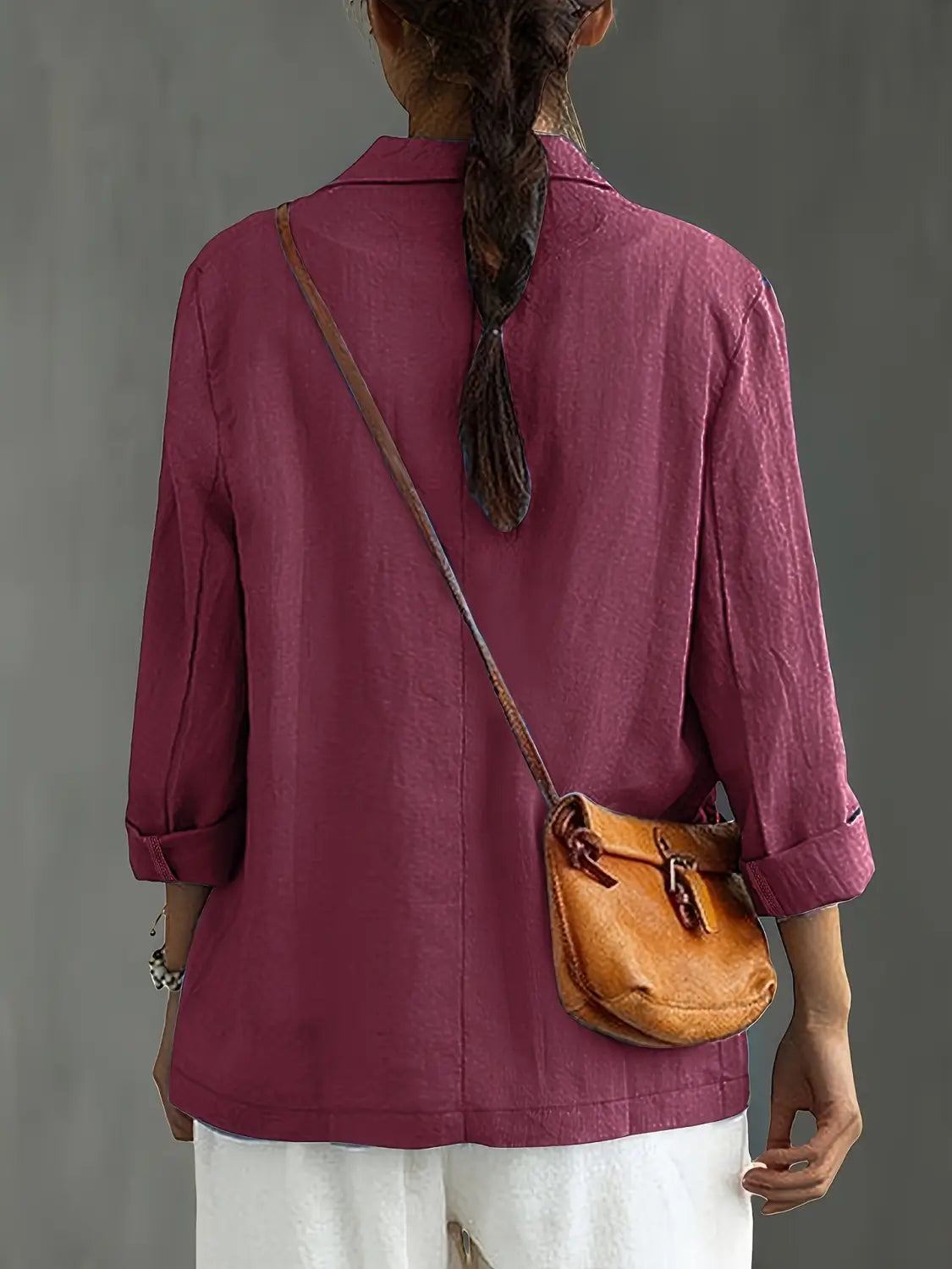 Un bolso cruzado de cuero color camel con cierre de solapa y correas marrones, combinado con un blazer de lino para mujer, casual y de trabajo.