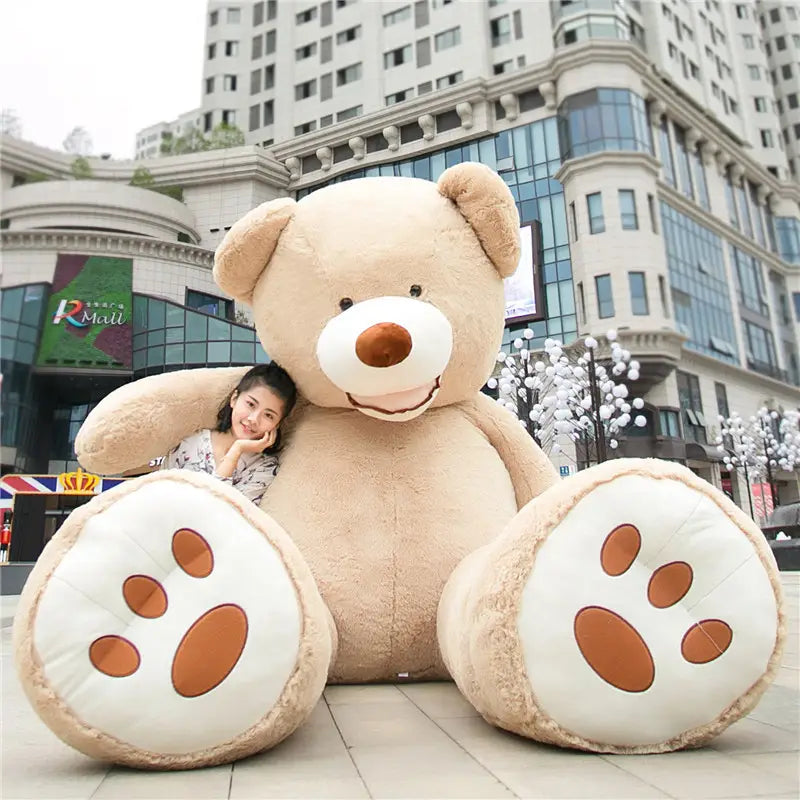 Ein flauschiger braunbeiger Riesen-Teddybär mit weißem Schnauzenbereich, brauner Nase und bestickten Pfotenabdrücken an seinen Füßen aus der Kollektion der Riesen-Teddybär-Plüschtiere, weiche Stofftiere, mit einer Größe von 1 Meter bis 3,4 Meter.