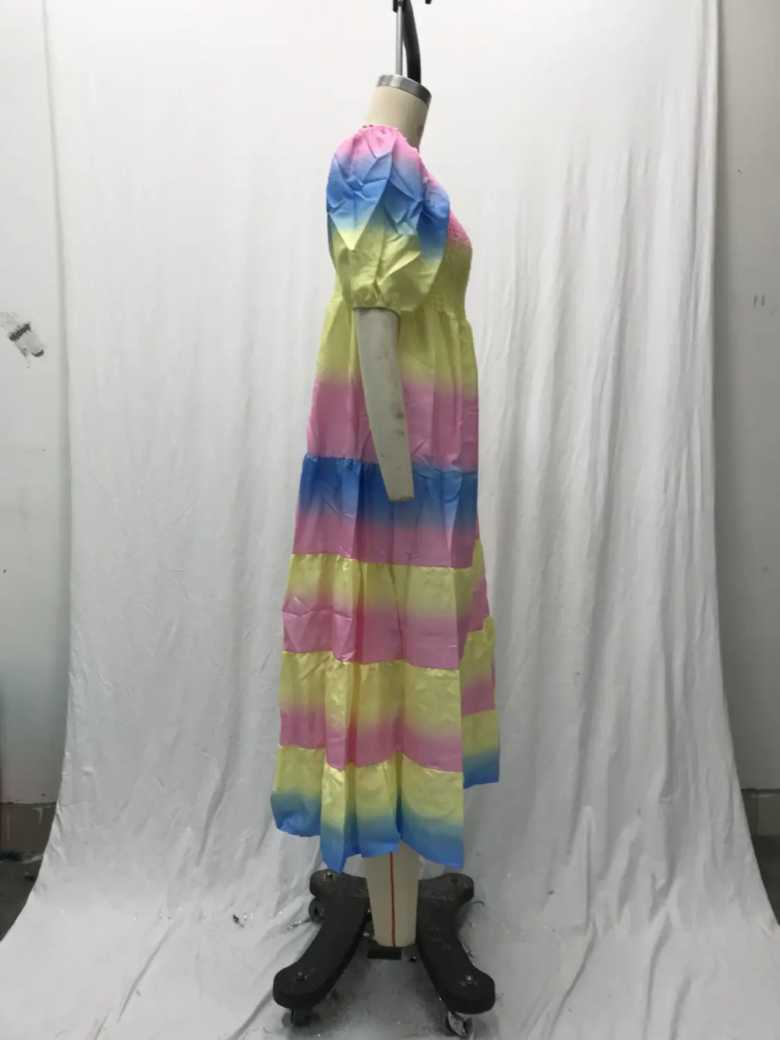 A vibrant rainbow-striped floral print smocked tiered midi dress with puffed sleeves and a square neckline displayed on a mannequin.