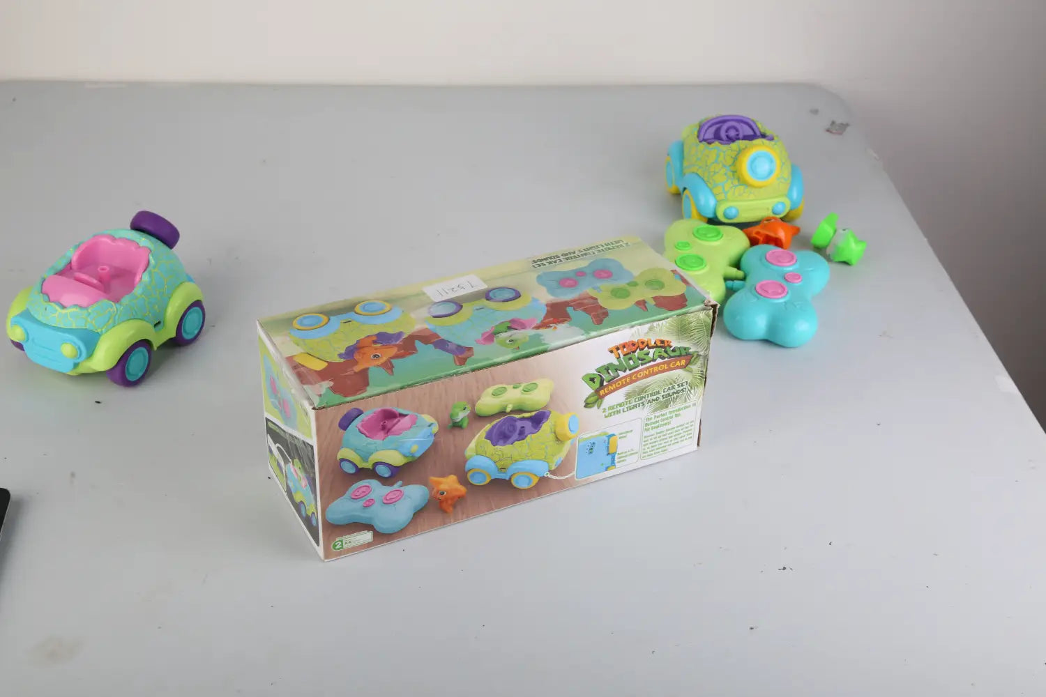 dinosaur remote control cars 2 pack for toddlers featuring colorful plastic toy cars in vibrant green blue and pink with playful dinosaur-themed designs.