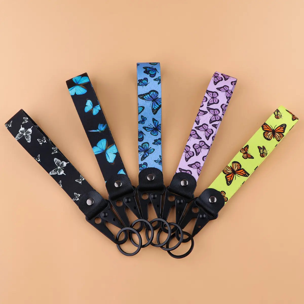 Five colorful butterfly-patterned butterfly wrist strap keychains with black metal clasps and rings for secure attachment.