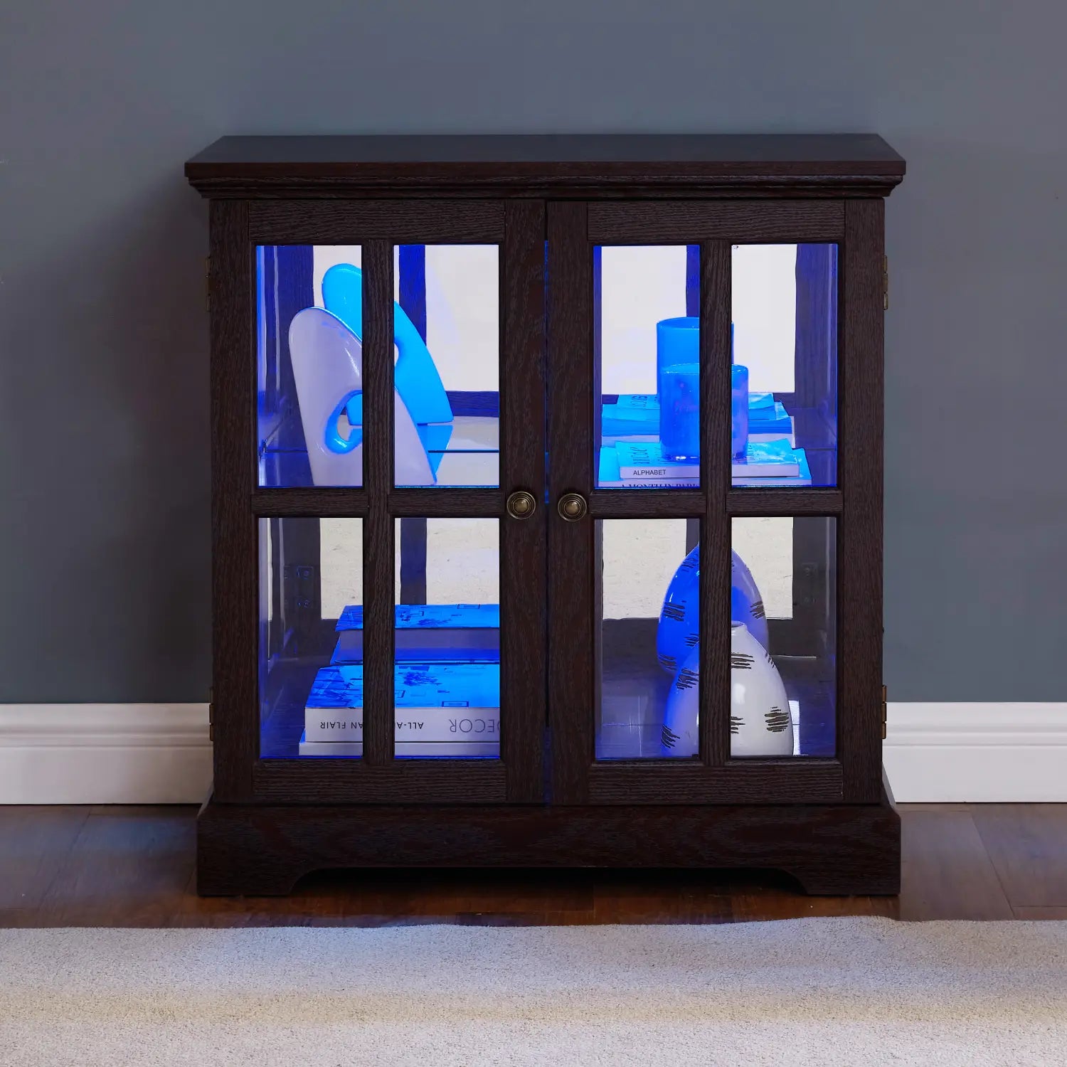 Led curio display cabinet made of dark wood with glass doors and blue internal led lighting featuring adjustable shelves.