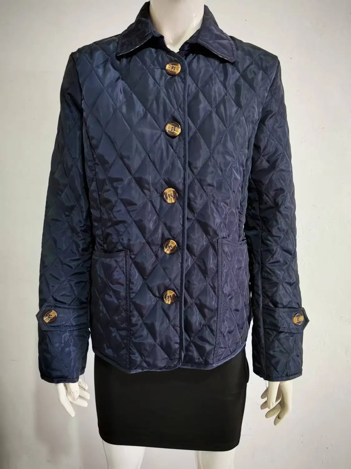 Dunkelblaue wattierte Baumwolljacke im Slim-Fit mit goldfarbenen Knöpfen, von vorne dargestellt.