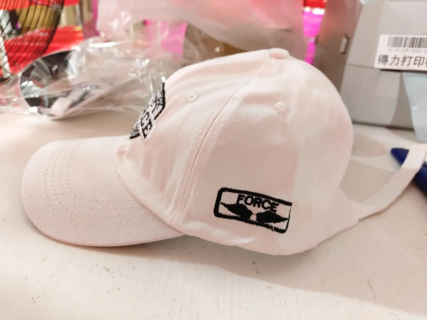 White baseball cap featuring black embroidered force logo and wing design on the side from the New York Force embroidered baseball cap collection.