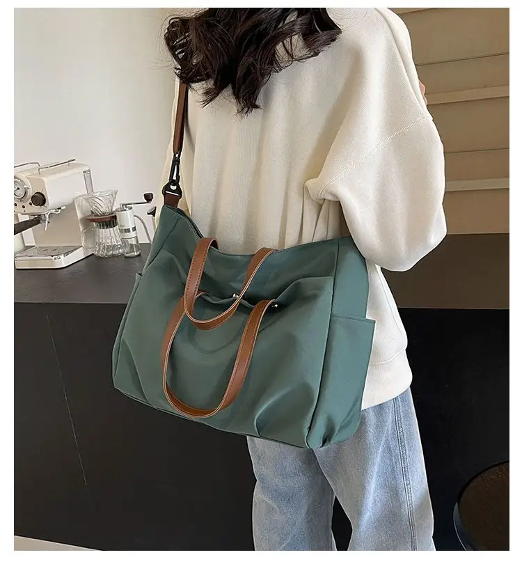 A teal large capacity canvas tote bag with brown leather handles and a matching shoulder strap.