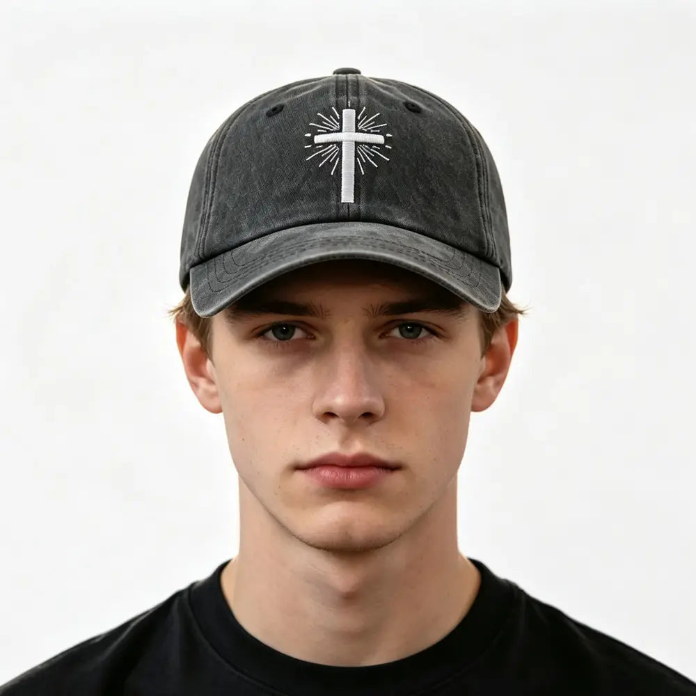 Casquette de baseball vintage délavée gris foncé, avec une croix blanche brodée et des lignes rayonnantes à l’avant.