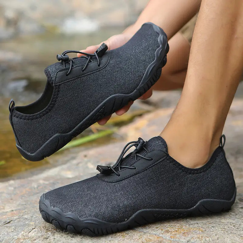 Black mesh water shoe with a rubber sole and adjustable laces, breathable and non slip for beach and trekking activities.