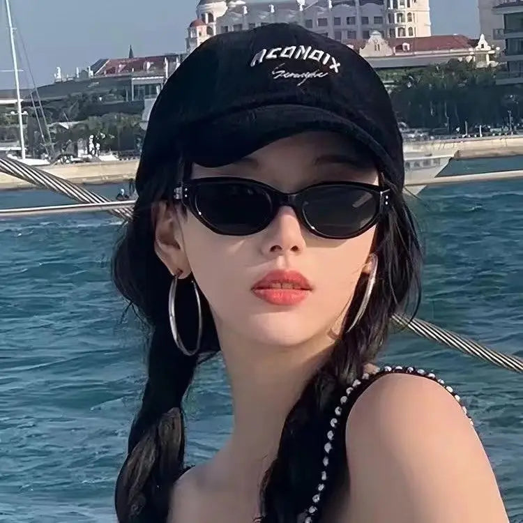 A black neonix baseball cap with a white embroidered logo shown alongside retro cat eye UV400 sunglasses featuring glossy modern frames.