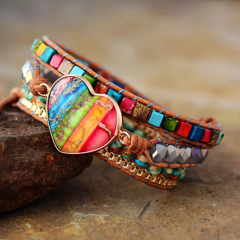 A vibrant multi-strand leather wrap bracelet featuring a central heart-shaped pendant with rainbow-colored stone inlay and colorful square beads in the rainbow heart imperial stone leather wrap bracelet.