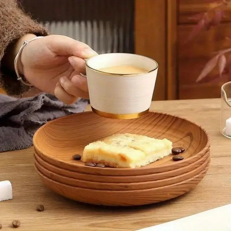 a hand holding a white ceramic coffee cup with a gold rim next to a set of wood grain plastic plates 10pc round striped design