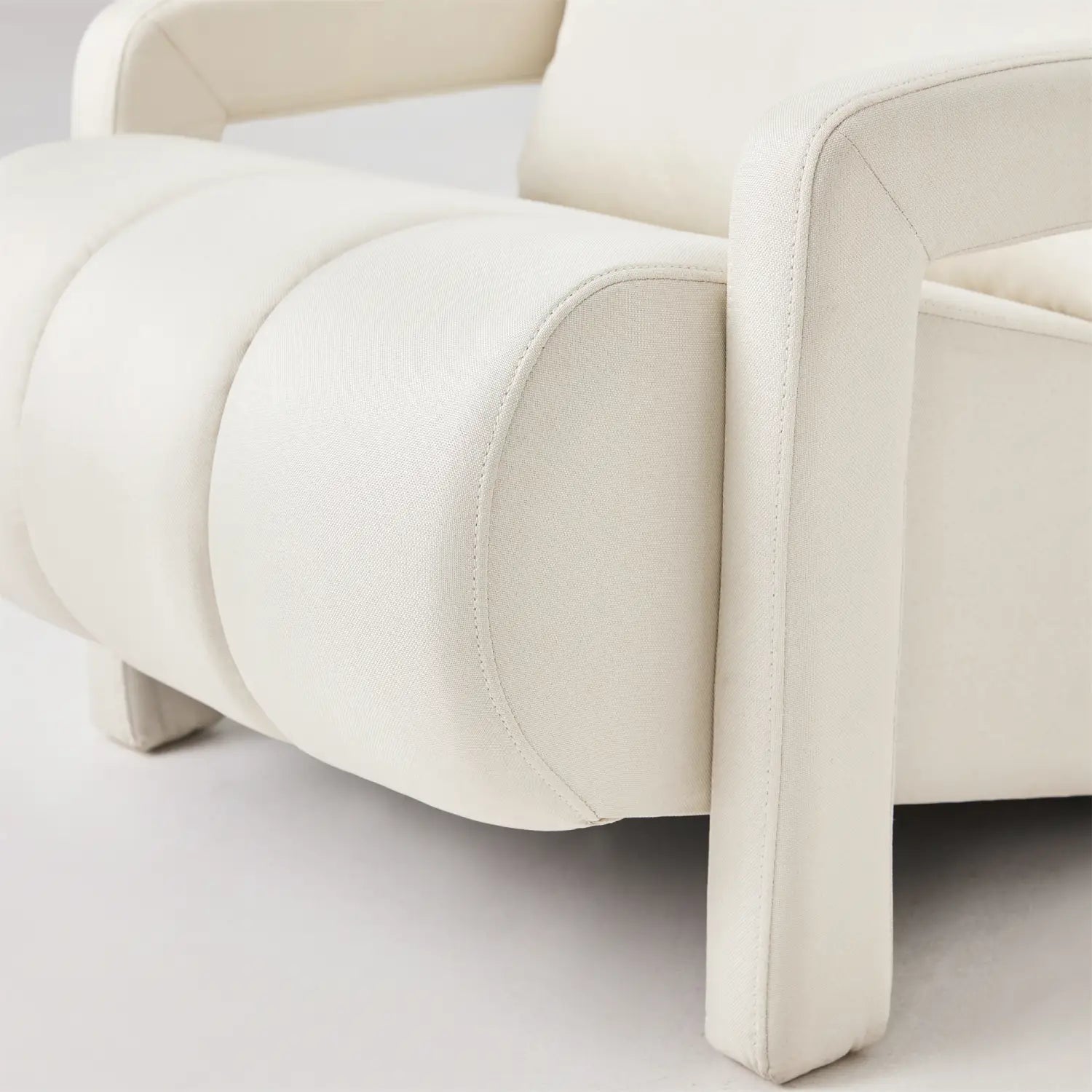 Cream-colored leather modern linen accent chair with segmented cushioned seat and clean-lined design for beige living room.