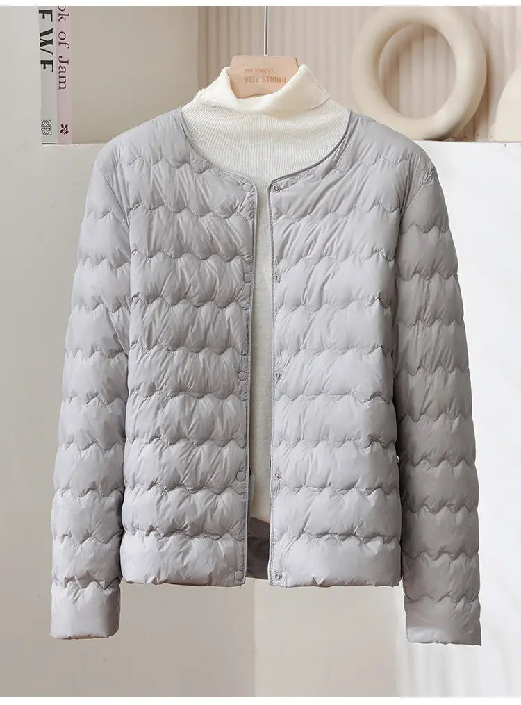 Light gray quilted puffer jacket with soft padded texture and button closure from the Puff Jacket Ruffled Crew Neck collection.