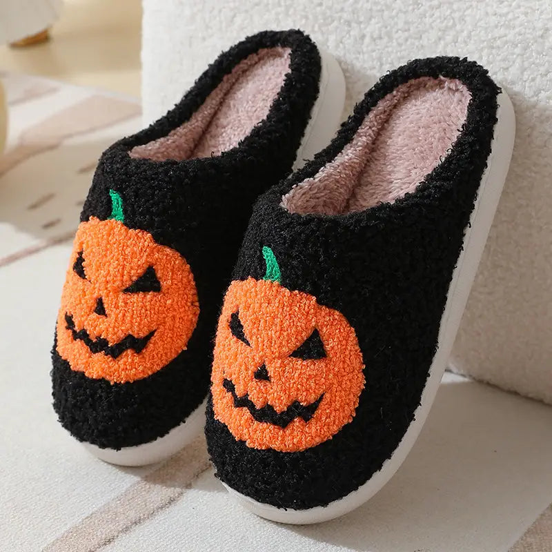 Black plush Halloween-themed slippers featuring orange embroidered jack-o-lantern faces with green stems lined with soft pink fleece in a product titled White Plush Jack-o-lantern Embroidered Halloween Slippers.