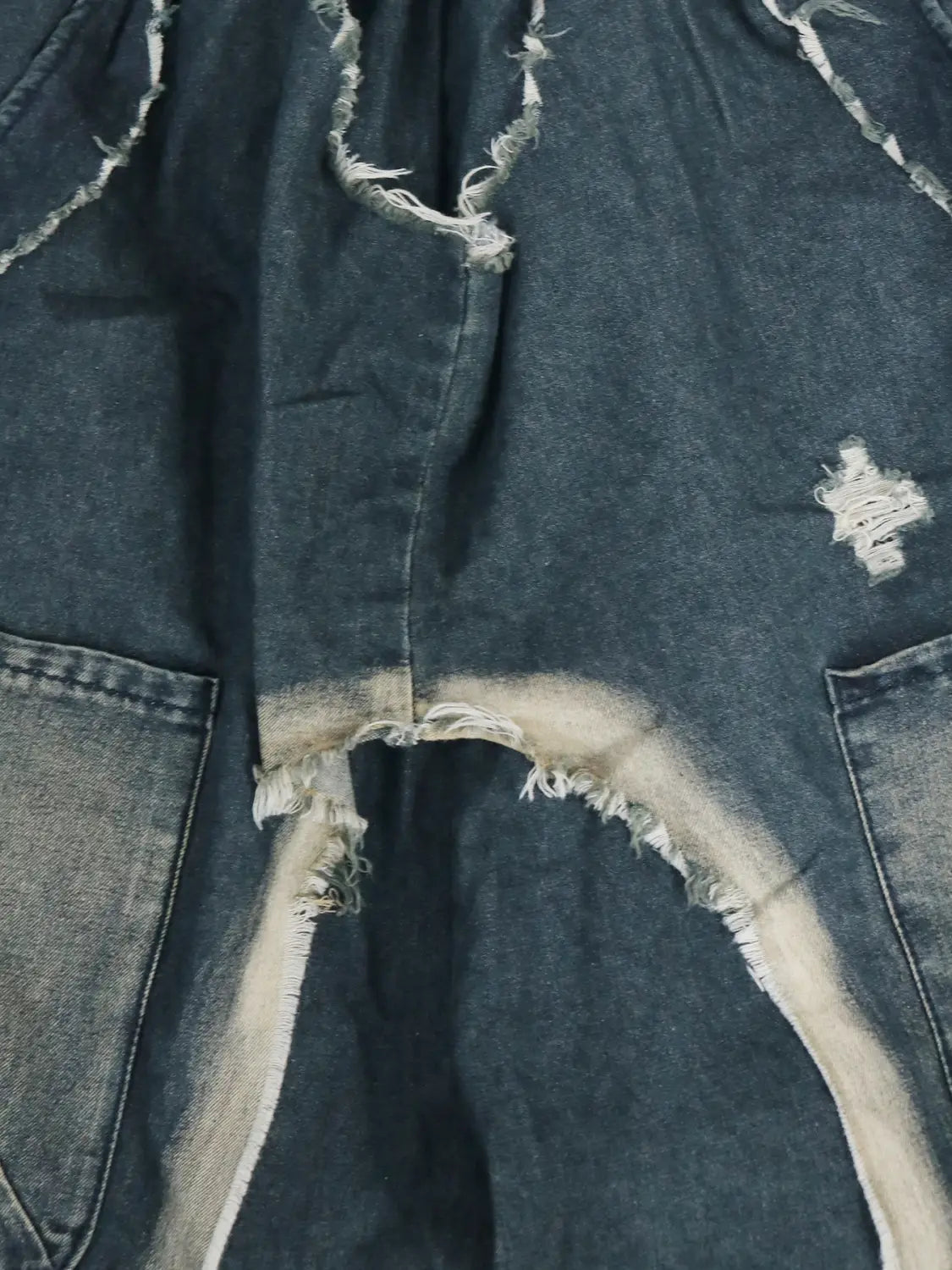 Dunkelblaue Jeans-Haremshosen im abgenutzten Patchwork-Look mit ausgefransten Kanten und einem verblassten Weißton entlang der Nähte.