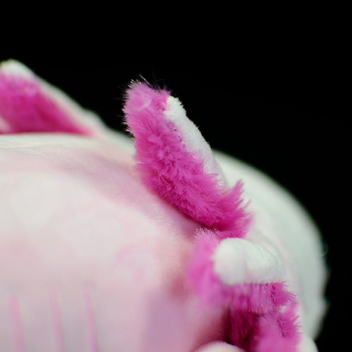 Eine flauschige rosa Axolotl-Weichtierpuppe im weichen, sechseckigen Dinosaurier-Design, 50 cm groß, mit flaumigen, leuchtend magentafarbenen Kiemen und weichen weißen Akzenten.