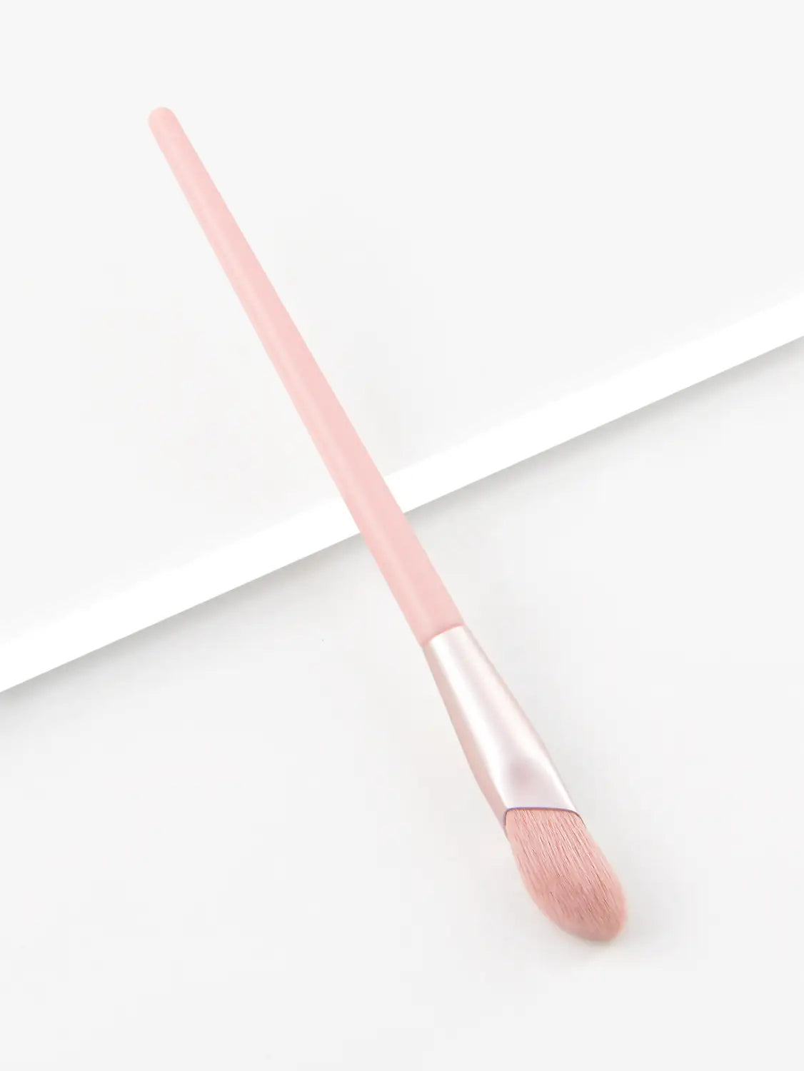 A soft pink finger belly makeup brush with a sleek slender handle and matching bristles designed as a professional contour tool.