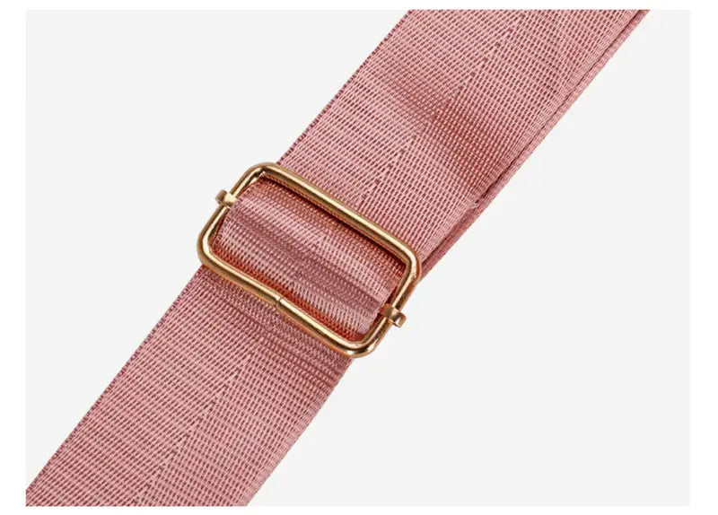 Pink woven strap with a gold-toned metal buckle on a waterproof oxford travel duffel for gym and sports.