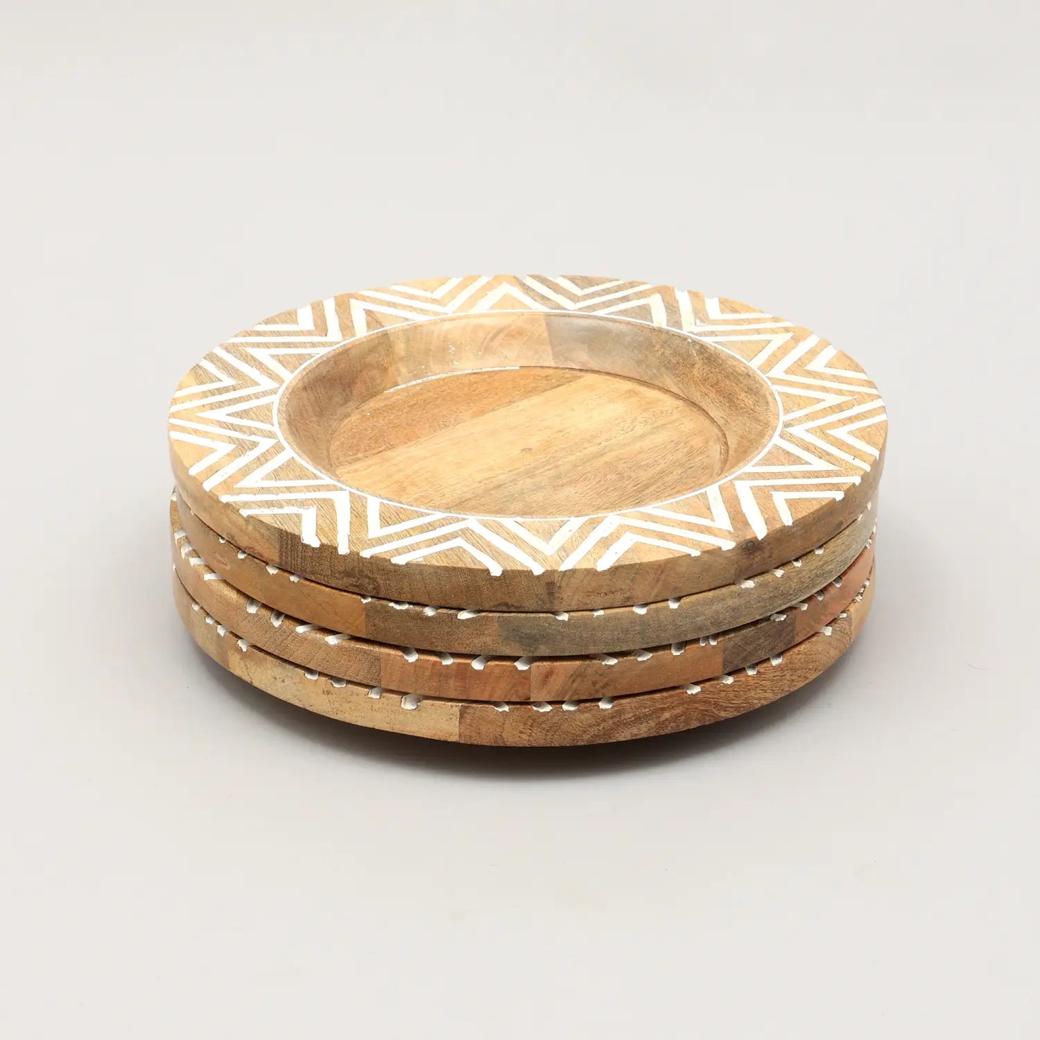 Juego de cuatro posavasos redondos de madera con patrones de incrustación geométrica blanca que coinciden con el diseño de incrustación geométrica de los platos portavelas de madera artesanales de 13 pulgadas.