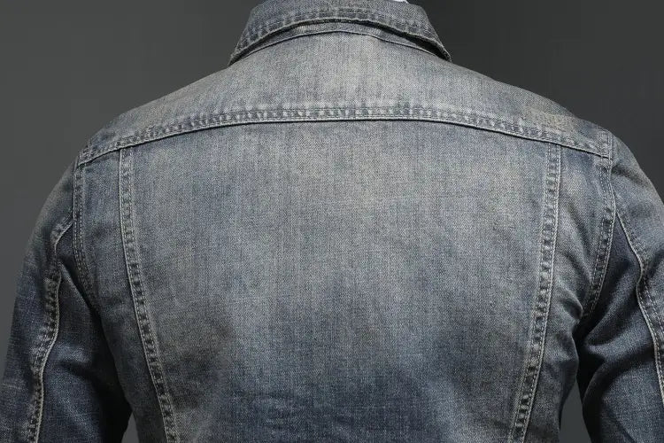 Distressed dark wash denim jacket for men featuring faded blue material with classic collar and visible stitching.