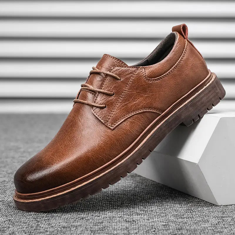 Black leather lace-up oxford shoe with brown rubber sole and stitched detailing for men’s business and casual wear.