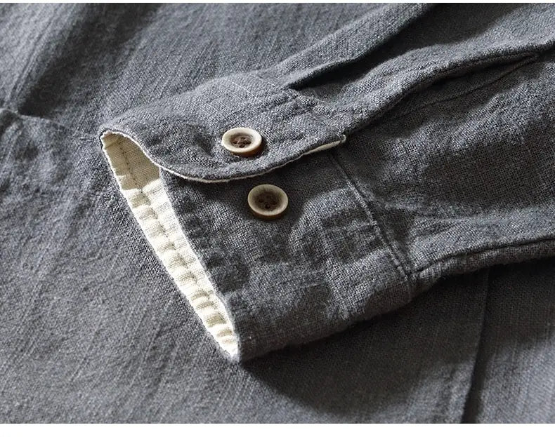 Puño de camisa de lino rami en gris oscuro, con dos botones de madera de color claro y un forro interior color crema en contraste, correspondiente a la camisa casual de cuello mandarina para caballero.